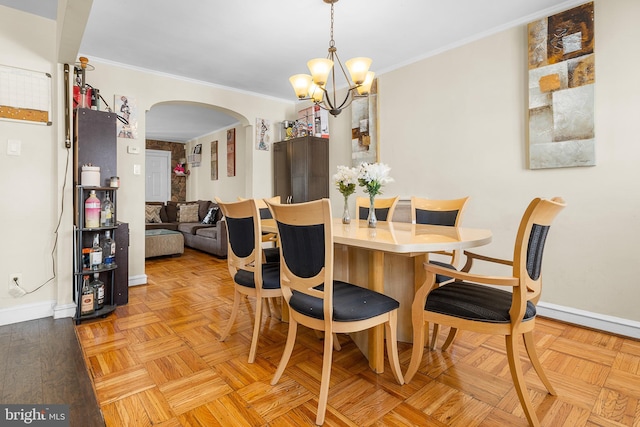 dining area with light parquet flooring, ornamental molding, and an inviting chandelier