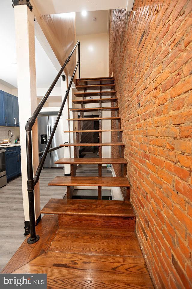 staircase featuring hardwood / wood-style floors and brick wall