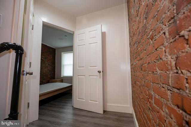 hall with dark hardwood / wood-style floors and brick wall