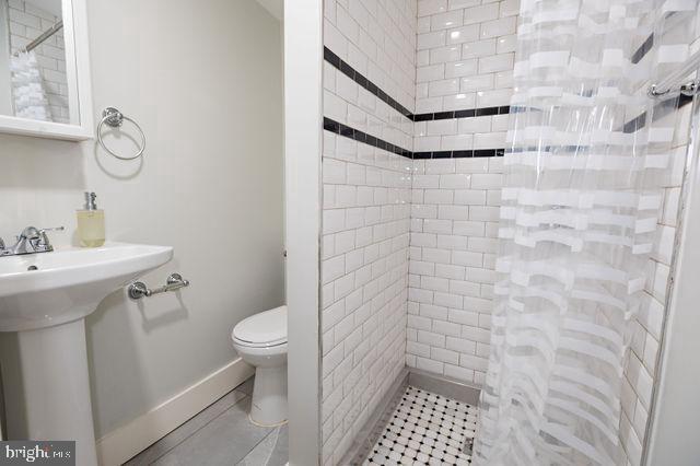 bathroom with a tile shower, toilet, and sink