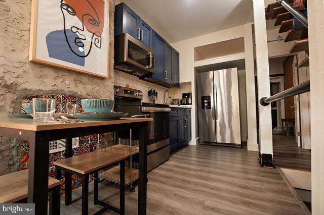 kitchen with hardwood / wood-style flooring, blue cabinetry, and stainless steel appliances