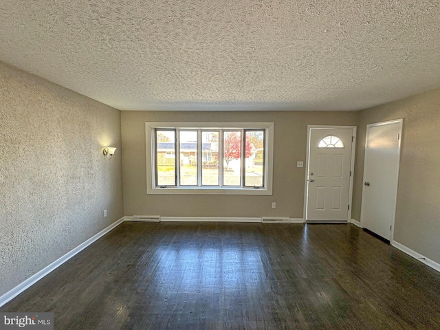 foyer entrance with dark hardwood / wood-style floors and a textured ceiling