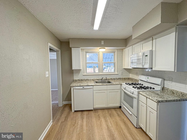 kitchen featuring sink, a textured ceiling, white appliances, white cabinets, and light wood-type flooring