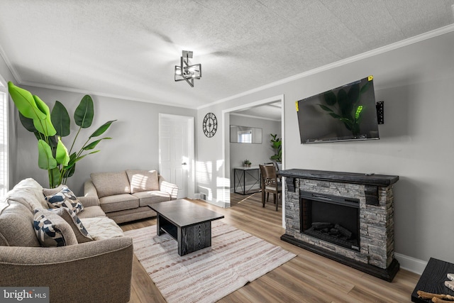 living room featuring hardwood / wood-style flooring, a stone fireplace, ornamental molding, and a textured ceiling