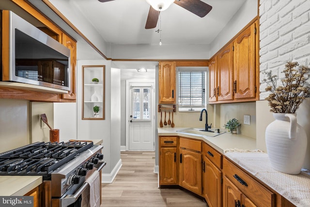 kitchen featuring ceiling fan, sink, stainless steel appliances, and light hardwood / wood-style flooring