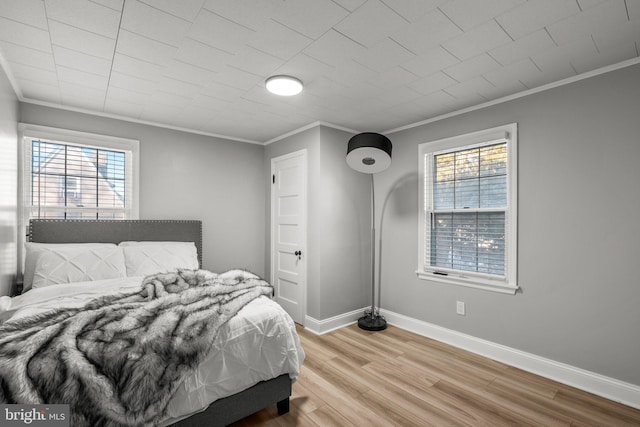 bedroom with hardwood / wood-style floors, multiple windows, and crown molding