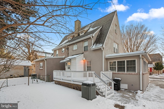 snow covered rear of property with a wooden deck and central AC