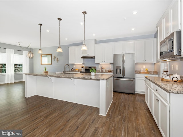 kitchen featuring white cabinetry, hanging light fixtures, dark hardwood / wood-style flooring, an island with sink, and appliances with stainless steel finishes