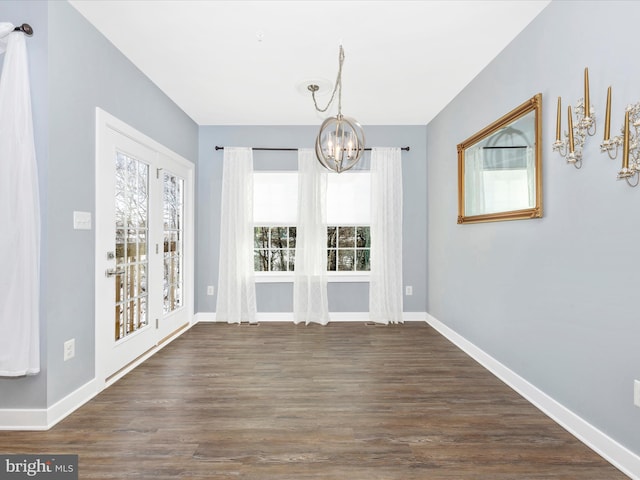 unfurnished dining area with dark hardwood / wood-style flooring and a notable chandelier