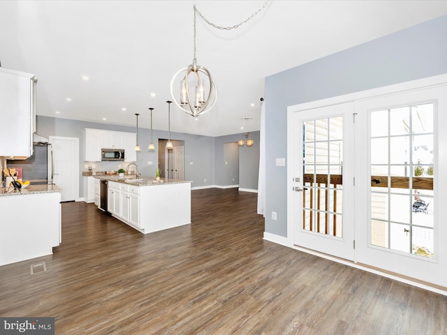 kitchen with appliances with stainless steel finishes, sink, pendant lighting, a chandelier, and white cabinetry