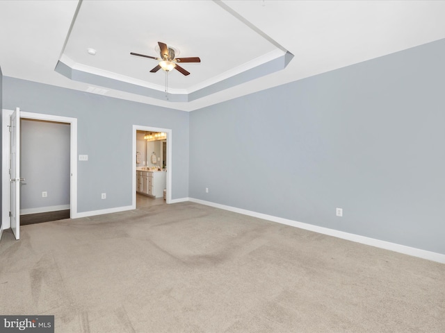 unfurnished bedroom featuring carpet, ensuite bath, a tray ceiling, ceiling fan, and crown molding