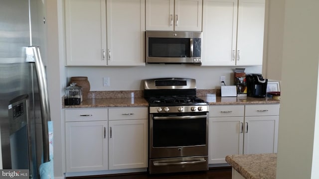 kitchen with white cabinetry, stainless steel appliances, and light stone countertops