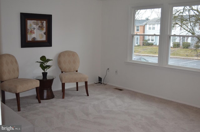 sitting room featuring baseboards, visible vents, and light colored carpet