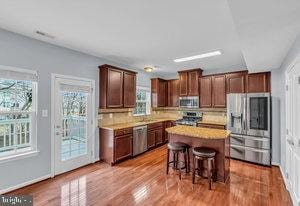 kitchen with appliances with stainless steel finishes, a breakfast bar, a kitchen island, and a wealth of natural light