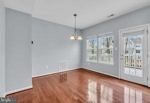 unfurnished dining area featuring an inviting chandelier, wood-type flooring, and a healthy amount of sunlight