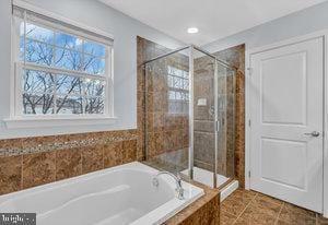 bathroom with separate shower and tub and tile patterned flooring