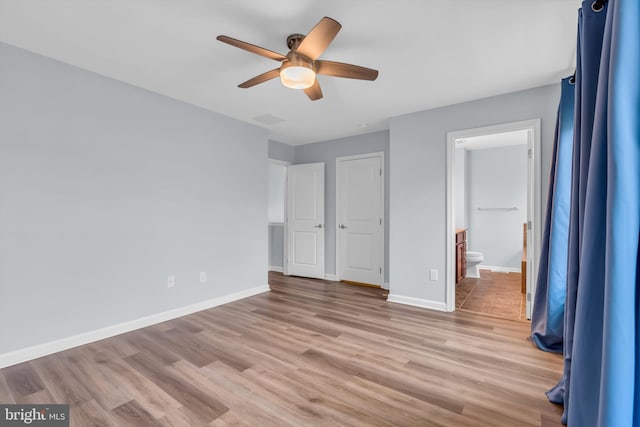 unfurnished bedroom featuring ceiling fan, ensuite bathroom, and light hardwood / wood-style flooring