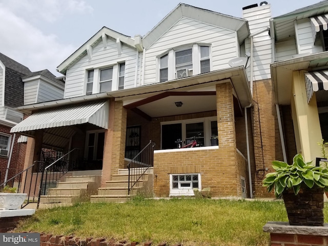 townhome / multi-family property with covered porch and brick siding