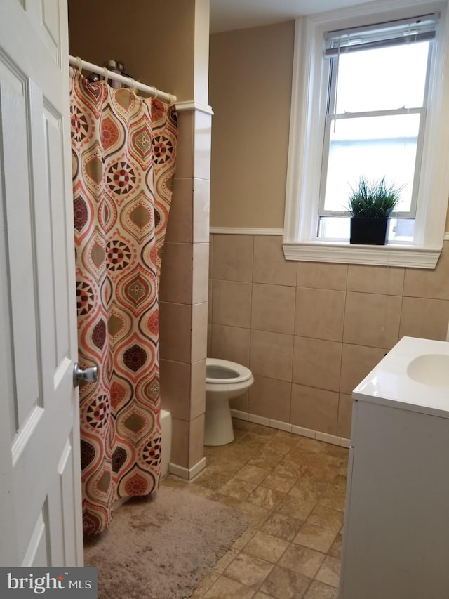 full bathroom featuring shower / bath combo, vanity, tile walls, and toilet