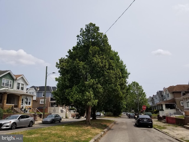 view of road with street lighting, traffic signs, sidewalks, a residential view, and curbs