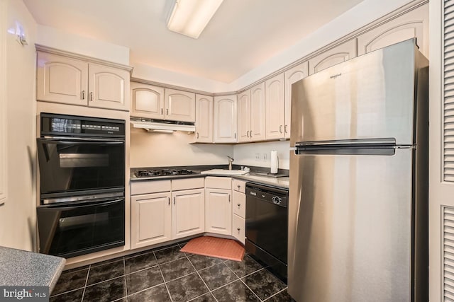 kitchen featuring cream cabinetry, sink, dark tile patterned floors, and black appliances