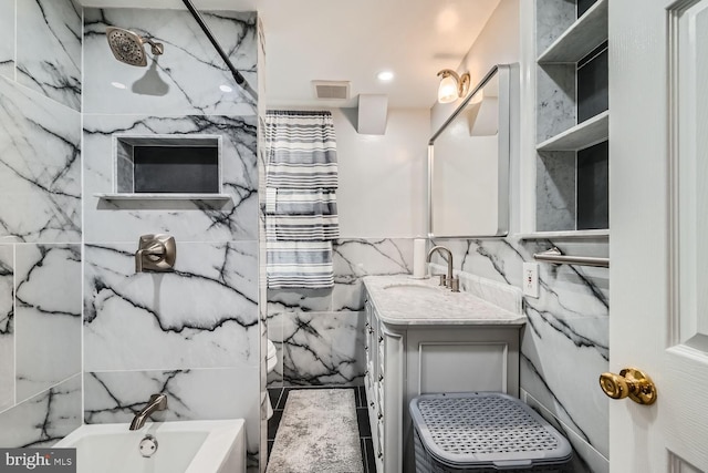 bathroom featuring vanity, toilet, a tub, and tile walls