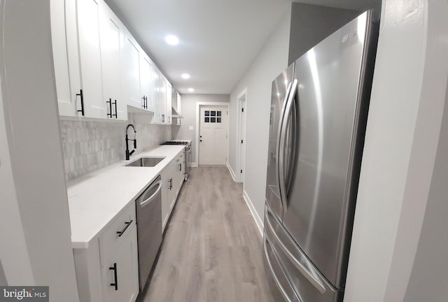 kitchen featuring sink, stainless steel appliances, backsplash, light hardwood / wood-style floors, and white cabinets