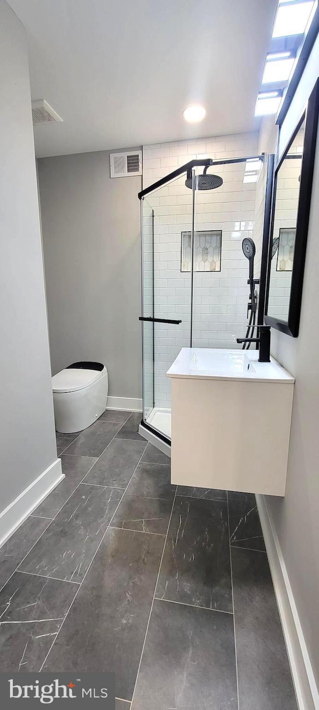 bathroom featuring vanity, a shower with shower door, and toilet