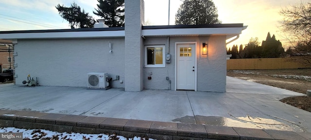 back house at dusk with ac unit and a patio