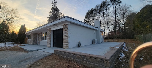 property exterior at dusk featuring central AC unit and a patio area