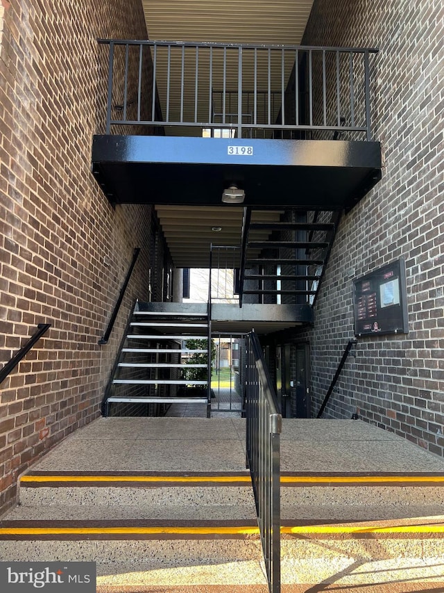 stairway with brick wall and a high ceiling