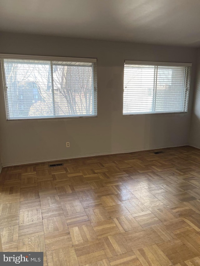 spare room with a wealth of natural light and light parquet flooring