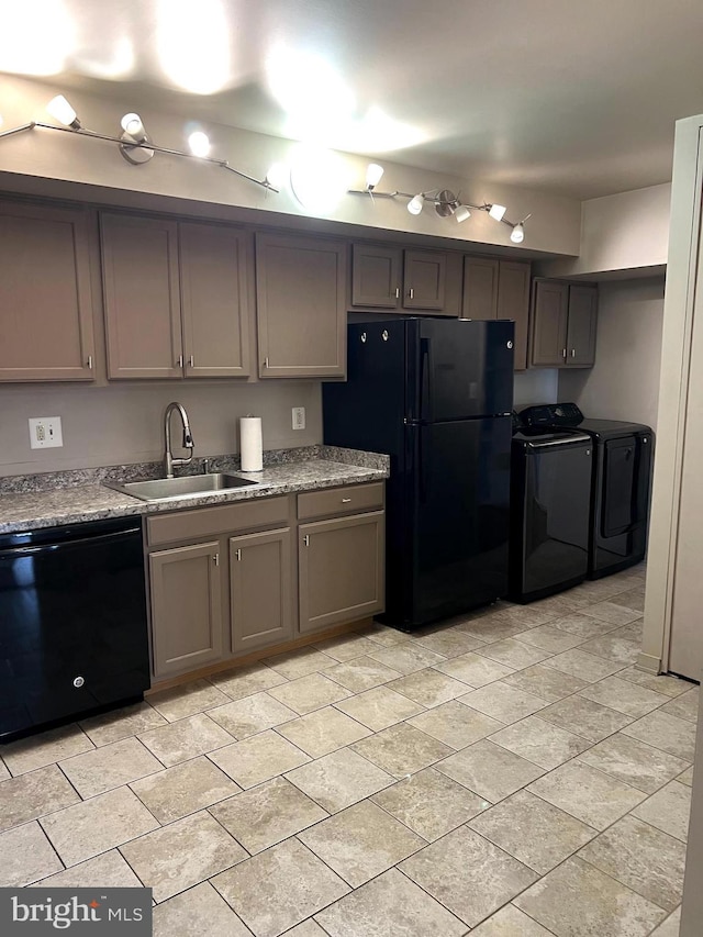 kitchen with washer and dryer, sink, light stone counters, and black appliances