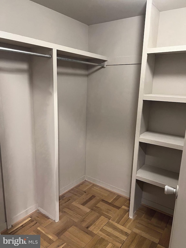 walk in closet featuring dark parquet flooring