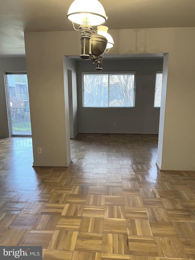 unfurnished dining area with plenty of natural light, parquet floors, and an inviting chandelier