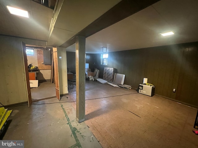 basement featuring electric panel and wood walls