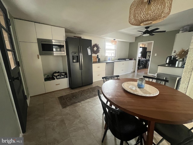 tiled dining space with ceiling fan and sink