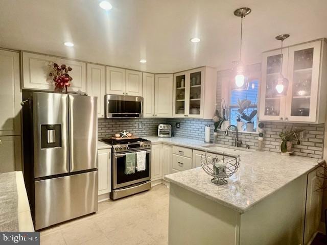 kitchen featuring light stone counters, stainless steel appliances, sink, pendant lighting, and white cabinets