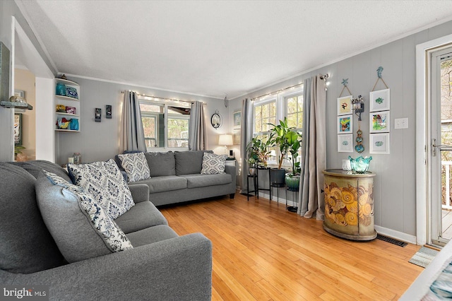 living room featuring hardwood / wood-style flooring, crown molding, a wealth of natural light, and a textured ceiling