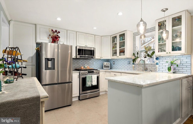 kitchen with decorative backsplash, appliances with stainless steel finishes, light stone counters, white cabinets, and hanging light fixtures