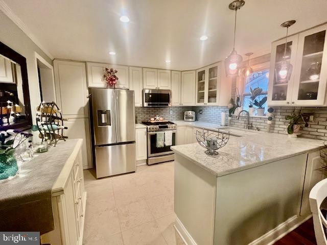 kitchen with white cabinets, sink, light stone countertops, decorative light fixtures, and stainless steel appliances