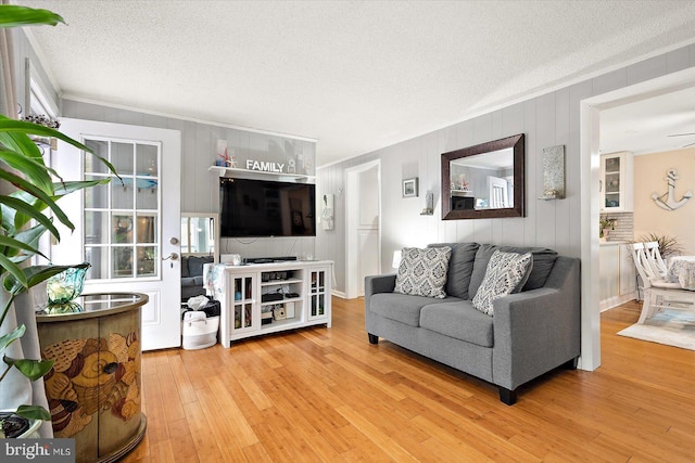 living room featuring hardwood / wood-style floors, ceiling fan, ornamental molding, and a textured ceiling