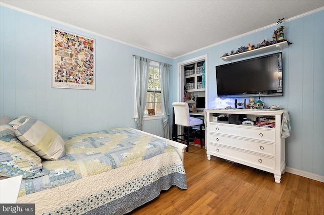 bedroom with crown molding, wood-type flooring, and a textured ceiling