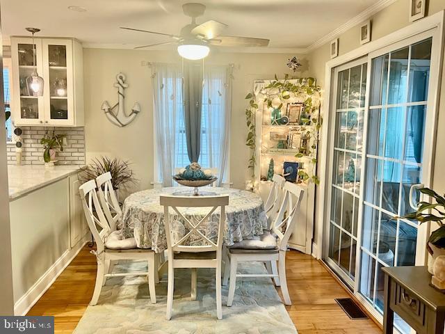 dining space with light wood-type flooring, ceiling fan, and ornamental molding