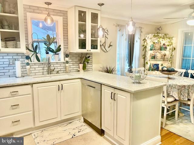 kitchen with white cabinetry, hanging light fixtures, light stone counters, stainless steel dishwasher, and light hardwood / wood-style floors