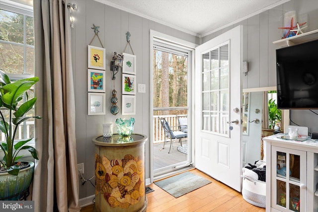 doorway featuring a textured ceiling, crown molding, hardwood / wood-style floors, and plenty of natural light