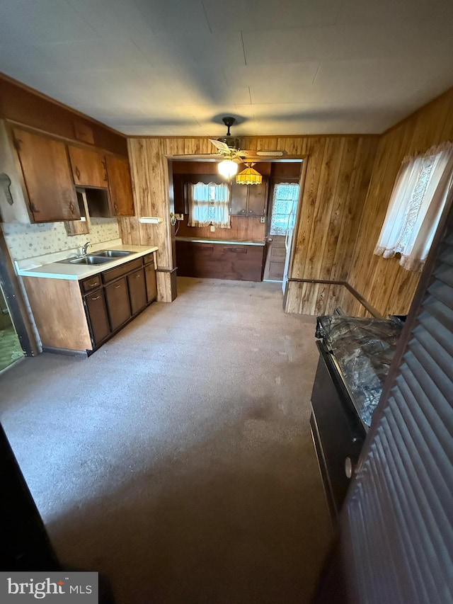 kitchen featuring ceiling fan, wood walls, and sink