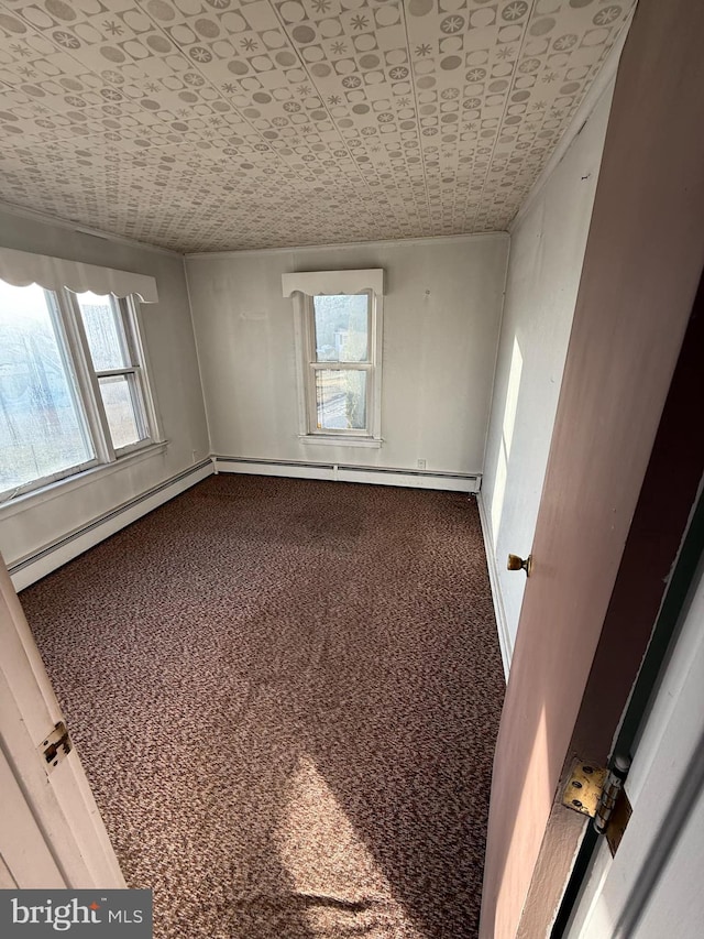 carpeted spare room with a baseboard heating unit