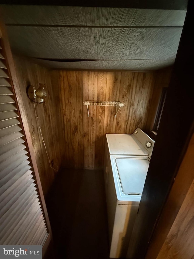 washroom with wooden walls and washer / dryer