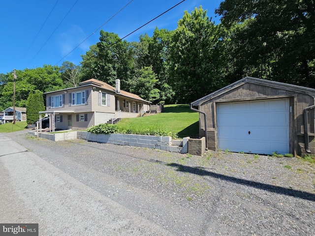 view of front of property with a garage, an outdoor structure, and a front yard